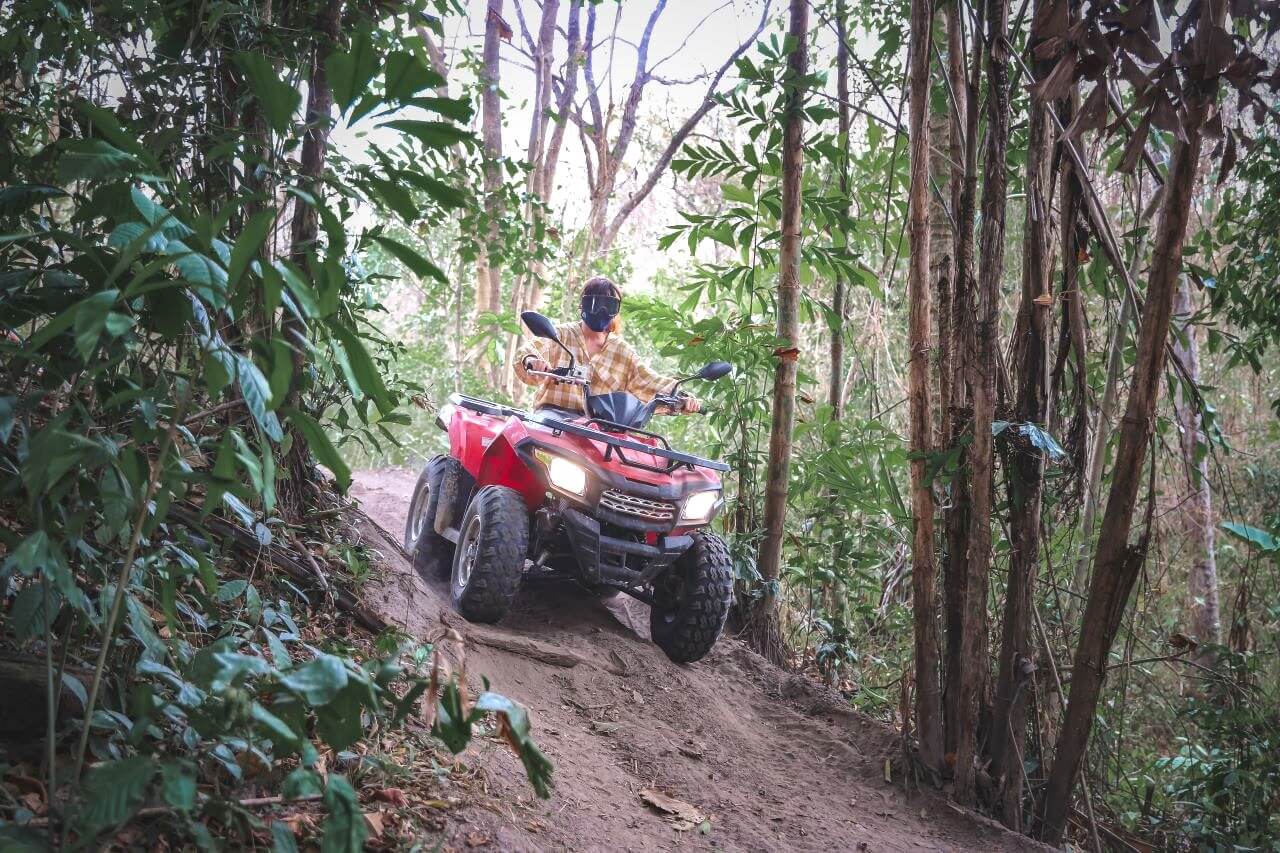 people-riding-atv-motorcycle-road-amidst-trees-forest