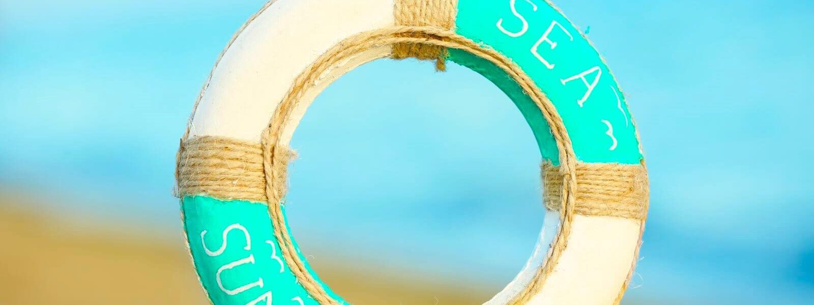 beautiful-life-buoy-sand-unfocused-sea-background