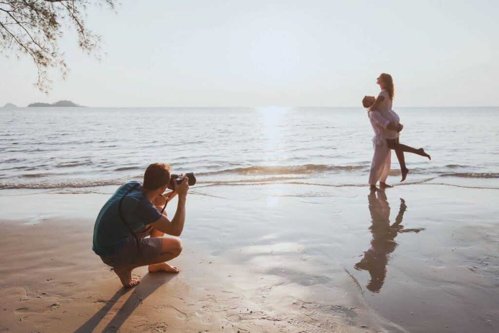 wedding-lifestyle-photographer-taking-photos-affectionate-couple-beach-sunset